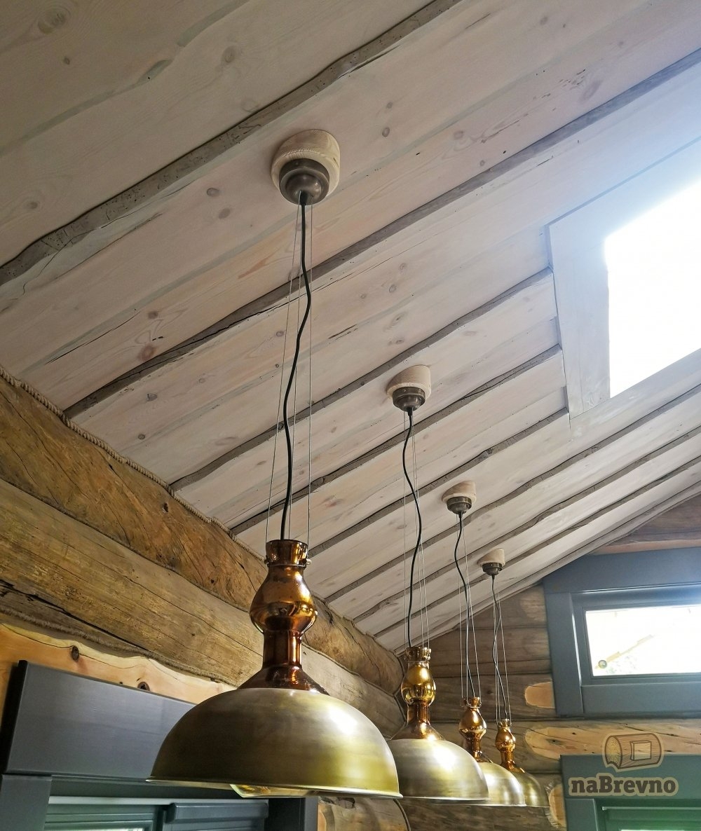 Группа латунных светильников на скошенном потолке из необрезной доски.